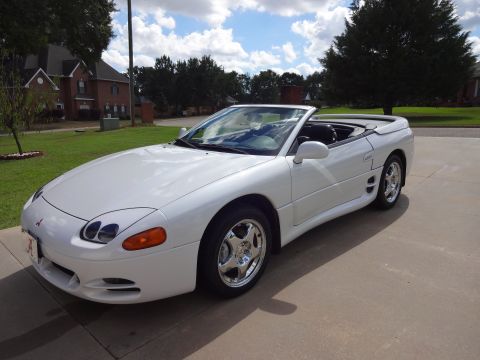 1995 Mitsubishi 3000GT - A white 1995 Mitsubishi 3000GT convertible is parked in front of a house on a sunny day.