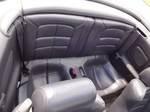 1995 Mitsubishi 3000GT - The interior of a car shows dark leather seats and seatbelts, with a visible watermark at the bottom right.