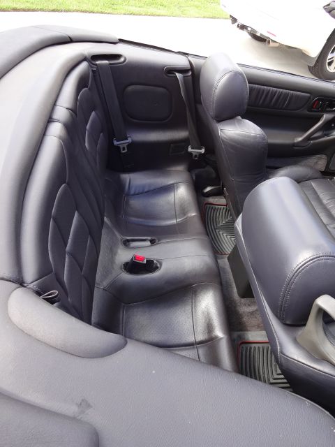 1995 Mitsubishi 3000GT - Interior view of a convertible's rear seats, with another car visible in the background.