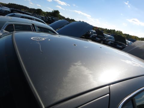 2001 Ford Crown Victoria - A collection of vehicles sit in a junkyard under a partly cloudy sky.