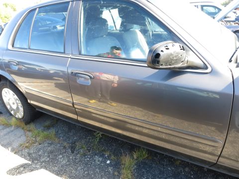 2001 Ford Crown Victoria - The side profile of a gray 2001 Ford Crown Victoria is visible, with a damaged side mirror and chrome wheel covers.