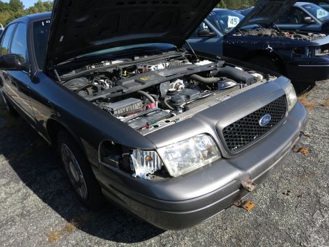 2001 Ford Crown Victoria - Front view of a 2001 Ford Crown Victoria, hood open, parked in an outdoor lot with other vehicles.