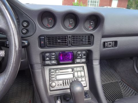 1995 Mitsubishi 3000GT - The interior dashboard of a 1995 Mitsubishi 3000GT features a distinctive purple digital climate control display and multiple gauges.