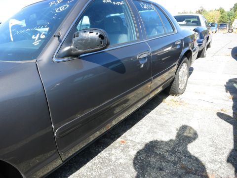 2001 Ford Crown Victoria - Side view of a 2001 Ford Crown Victoria, showing its body lines and a missing side mirror.