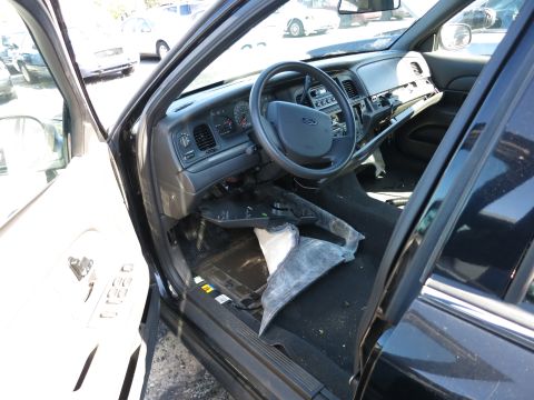 2001 Ford Crown Victoria - The interior of a black vehicle shows a disassembled dashboard and steering wheel, with other cars visible in the background.