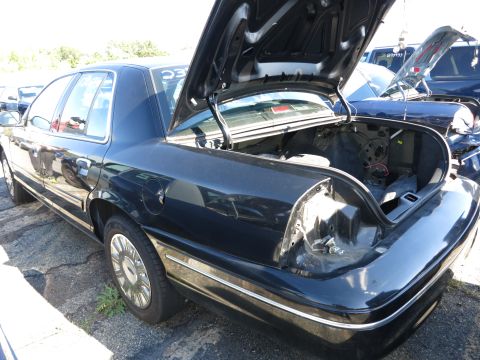 2001 Ford Crown Victoria - The rear of a dark 2001 Ford Crown Victoria is shown with its trunk open, revealing an empty cargo area.