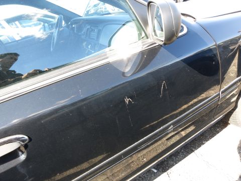 2001 Ford Crown Victoria - Scratches on the side of a black car door, with interior visible through the window.