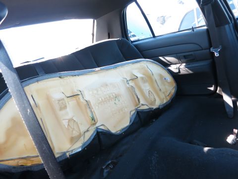 2001 Ford Crown Victoria - The interior of a car shows a damaged seat cushion with exposed foam and upholstery.