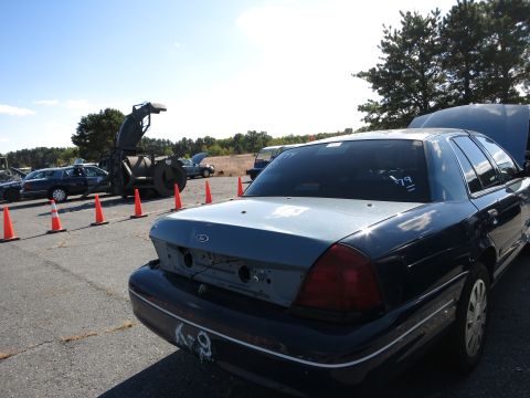 2001 Ford Crown Victoria - A dark blue Ford Crown Victoria is parked outdoors with its hood open, showing damage to the rear.