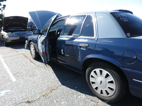 2001 Ford Crown Victoria - Two Ford Crown Victorias are parked side-by-side, with one having its doors and hood open.