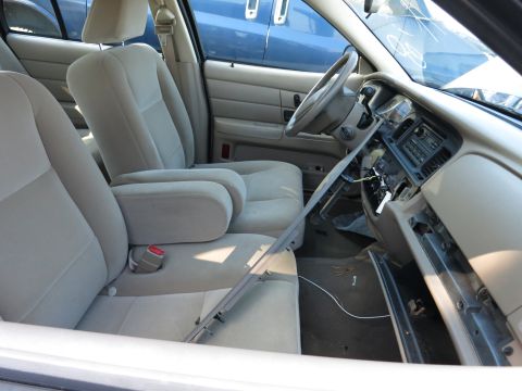 2001 Ford Crown Victoria - The interior of a 2001 Ford Crown Victoria shows tan cloth seats and a dashboard with exposed wiring and missing panels.