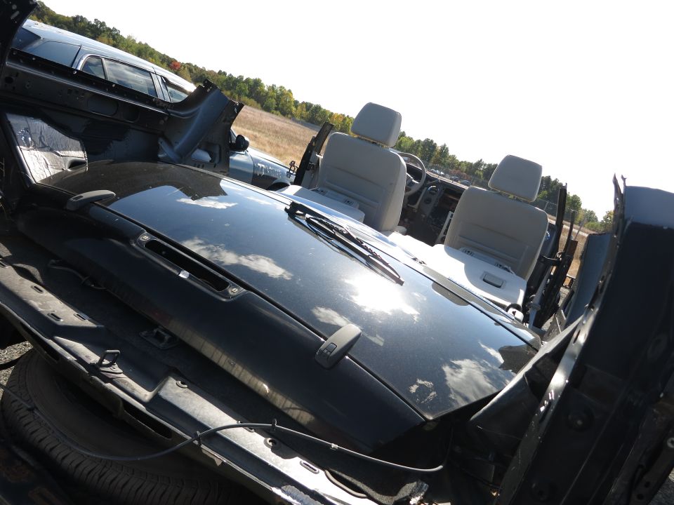 Black car hood and interior with light grey seats and dashboard, viewed from above