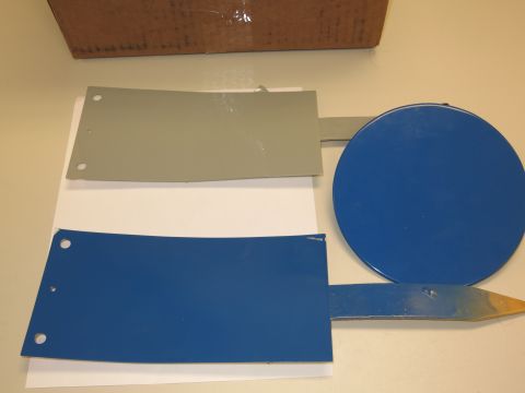 1991 Ford LTD Crown Victoria - Various metal components, including a blue circle and two rectangular plates, are laid out on a white surface.