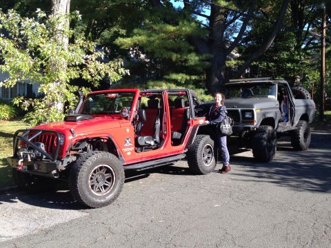 1979 Ford Bronco - A 1979 Ford Bronco is parked next to a red Jeep, its lifted suspension and off-road tires.