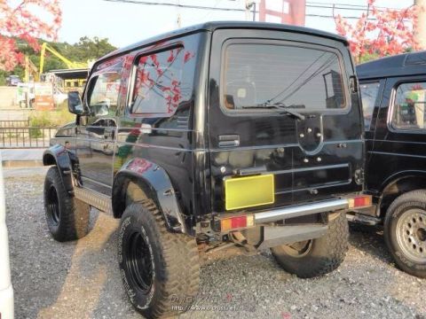 1996 Suzuki Samurai - Rear view of a black off-road SUV with aftermarket wheels and tires, parked outdoors.