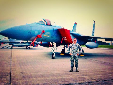 1979 Ford Bronco - An airman poses in front of a blue fighter jet on an airfield, with another jet visible in the background.