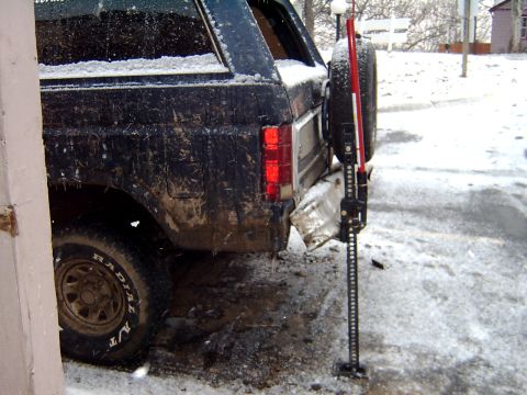 1982 Ford Bronco - Muddy and snow-covered 1980s Ford Bronco with a Hi-Lift jack attached to the rear spare tire mount.
