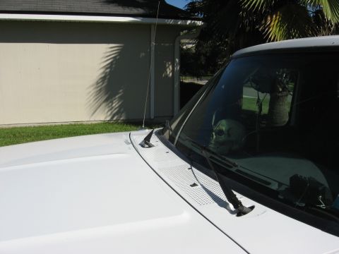 1994 Ford Bronco - White truck with a skull decoration on the dashboard, parked outside a building.