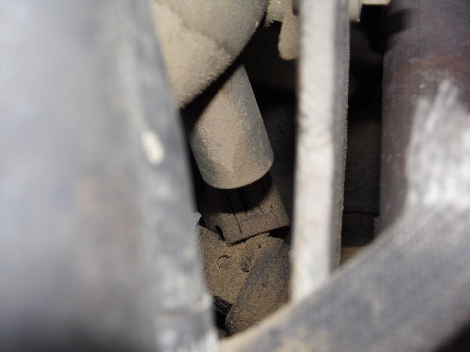 Close-up of a dusty engine part, possibly a hose connector or sensor