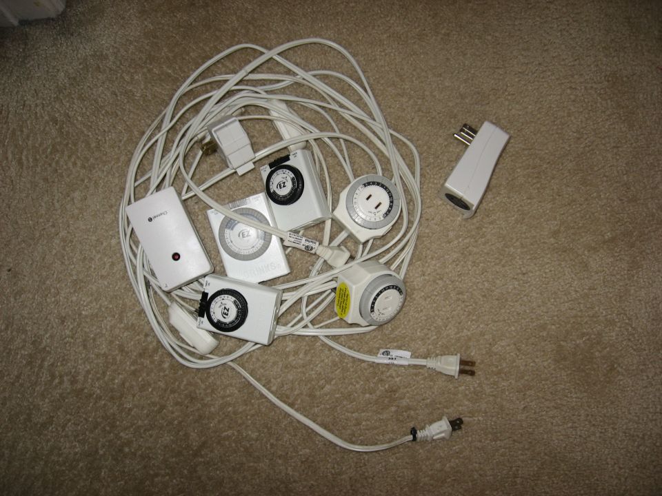 Pile of white electrical timers and cords on a carpeted floor