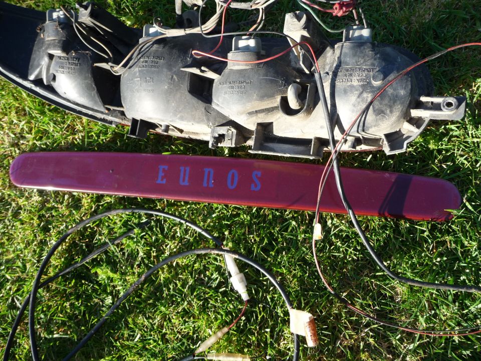 Car taillight assembly with wiring and a red trim piece with 'EUNOS' text