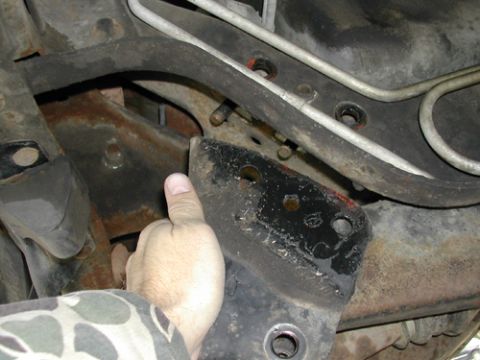 1996 Ford Bronco - Underside view of vehicle frame and suspension components, with a hand pointing to a bracket.