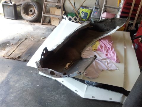 1976 Ford Ranchero - Car fender and hood parts are laid out on the floor in a garage.