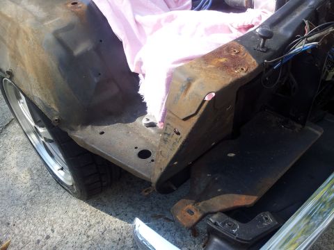 1976 Ford Ranchero - The image shows the inner fender and engine compartment of a vehicle, with visible rust and some pink insulation material.