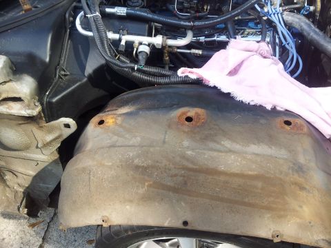 1976 Ford Ranchero - Close-up view of an engine bay and a heavily rusted fender well, showing air conditioning lines and a pink cloth.