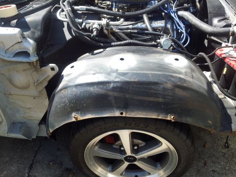 1976 Ford Ranchero - The front wheel well and engine compartment of a vehicle are shown, with visible wiring and engine parts.