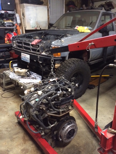 1988 Suzuki Samurai - A Toyota truck is in a garage with its engine hoisted out for maintenance or repair.