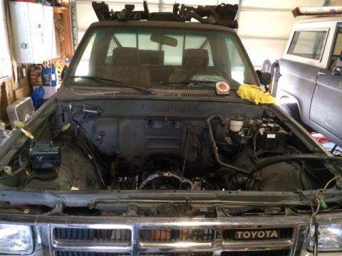 1988 Suzuki Samurai - The engine bay of a truck is shown with the transmission removed, revealing the engine block and other components.