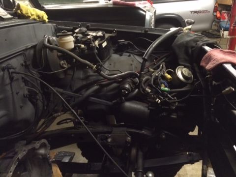 1988 Suzuki Samurai - Engine bay components and wiring are visible, with a Toyota truck in the background.