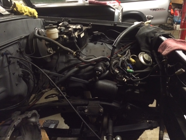 Engine bay with visible wiring and components, part of a Toyota truck in background