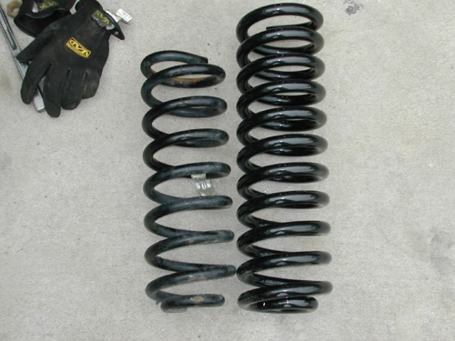 Two black coil suspension springs and a pair of black work gloves with yellow logos