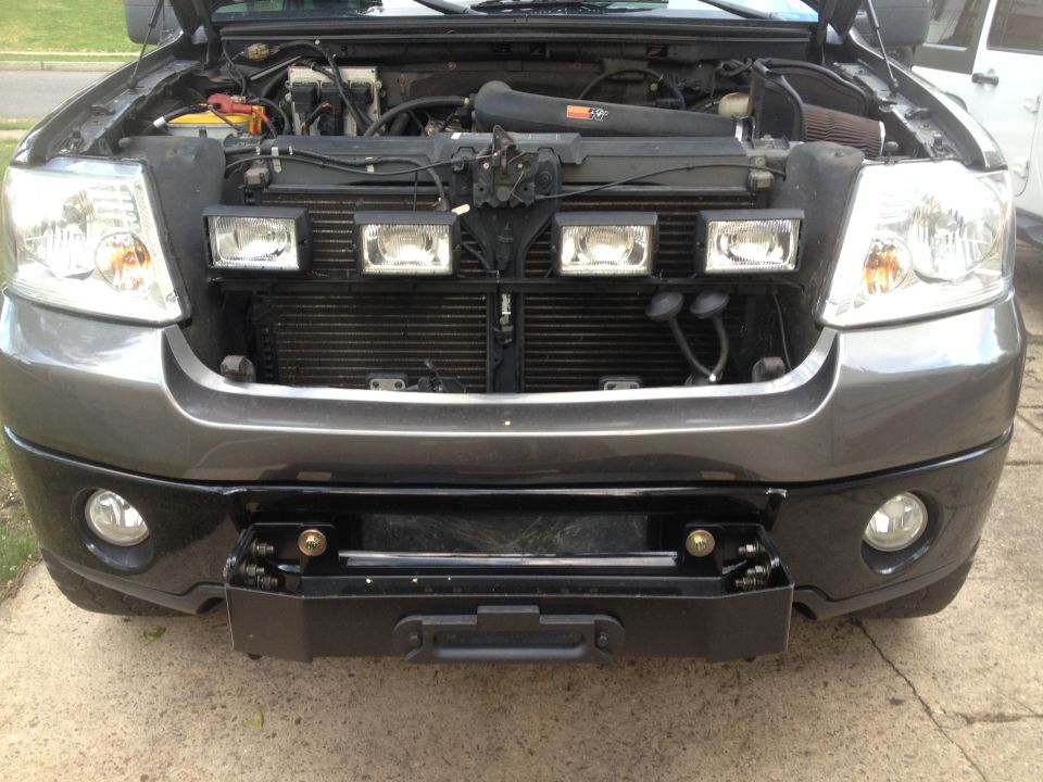 Truck front end, hood open showing engine. Has aftermarket bumper and lights