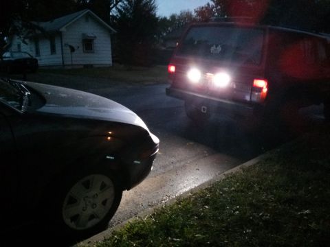 1986 Ford Bronco - Two SUVs are parked on a residential street as darkness falls.
