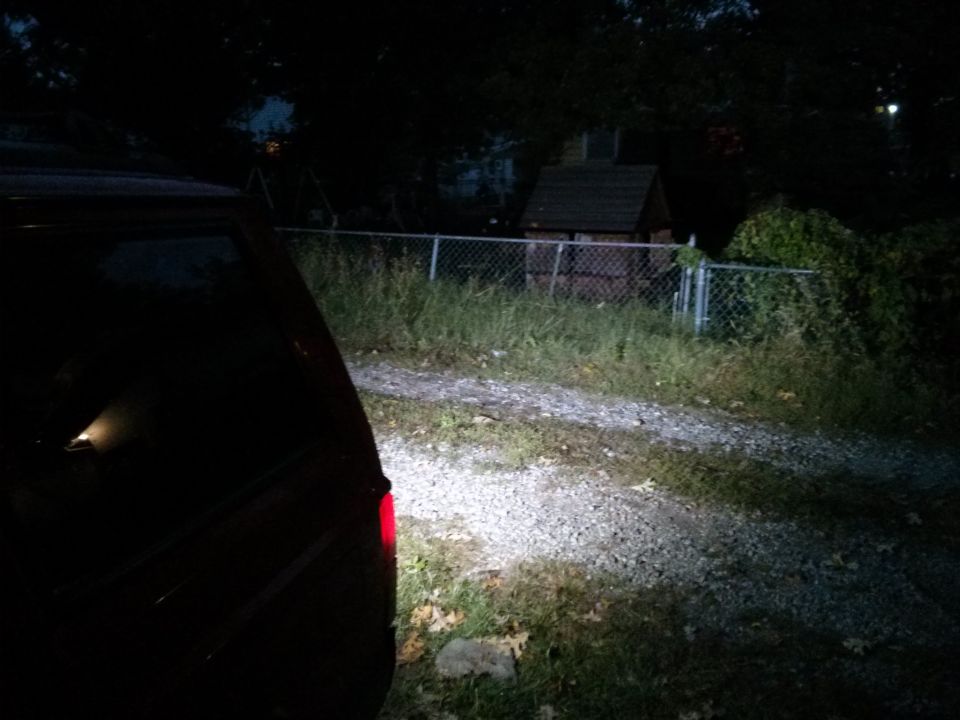 back of a dark SUV parked on a gravel driveway at night