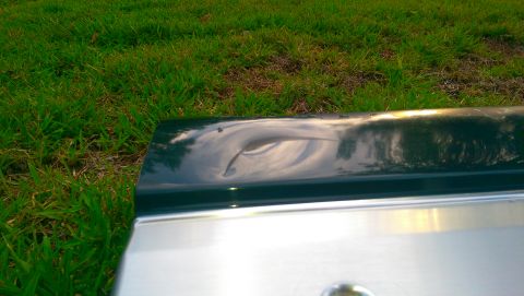 1996 Ford Bronco - Close-up of a damaged car tailgate with a dent on the upper panel.