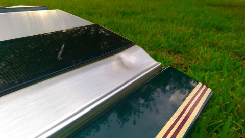 1996 Ford Bronco - A close-up view of a damaged car tailgate section with decorative stripes and brushed metal accents.