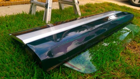 1996 Ford Bronco - A car's tailgate trim piece with peeling paint is shown resting on grass.