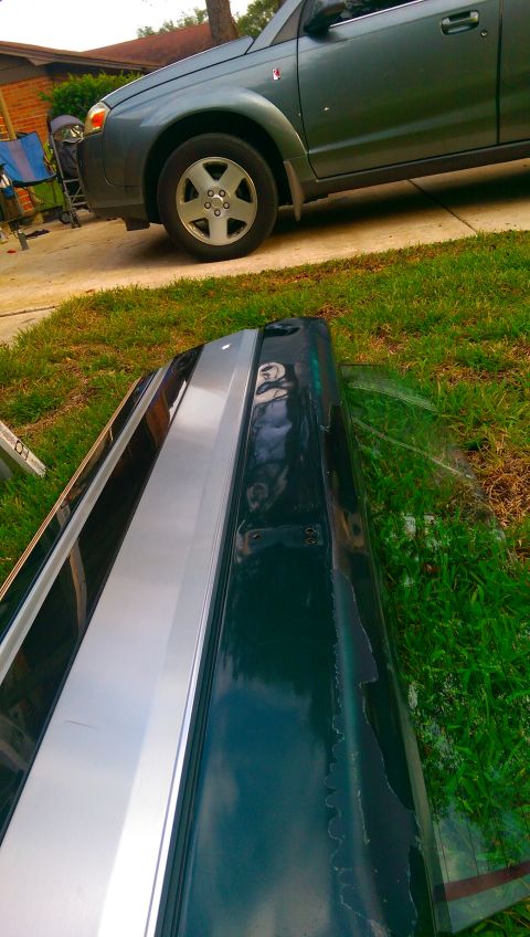 1996 Ford Bronco - A detached car bumper lies on the grass next to a green SUV.