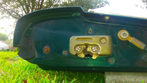1996 Ford Bronco - The interior of a vehicle's tailgate shows the metal latching mechanism and surrounding hardware.