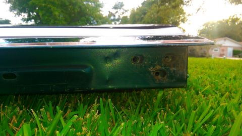 1996 Ford Bronco - Close-up of a damaged green tailgate lying on grass, showing rust and dents.