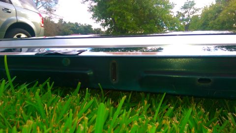 1996 Ford Bronco - A close-up view of a vehicle's tailgate, with grass in the foreground and another vehicle in the background.