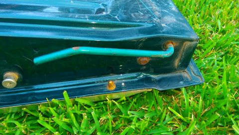 1996 Ford Bronco - Dark green painted sheet-metal panel with mounting studs and a teal-painted tube resting on green grass outdoors.