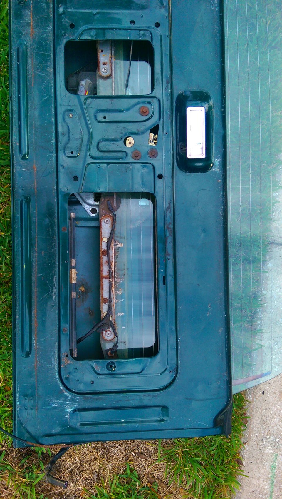 Interior of a dark green Ford Bronco tailgate, showing the mechanism and window frame