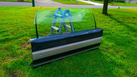 1996 Ford Bronco - A detached vehicle door rests on a grassy lawn, supported by a ladder.
