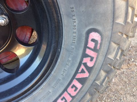 1996 Ford Bronco - A close-up view of a tire with 'GRAVEL' painted on the sidewall, mounted on a black wheel.