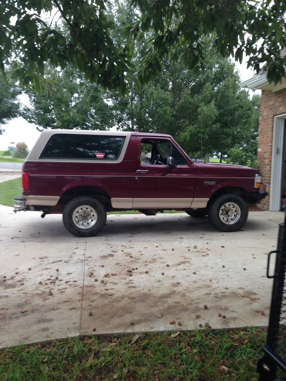 Maroon and tan Ford Bronco with aftermarket wheels parked on a concrete driveway
